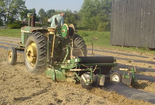 Tractor laying plastic to form raised planting beds