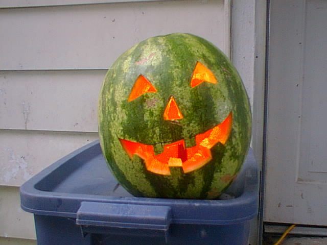 A watermelon carved like a jack-o-lantern glowing for fall